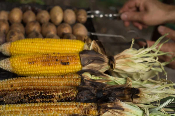 Чоловік пече кукурудзу і картоплю на грилі — стокове фото