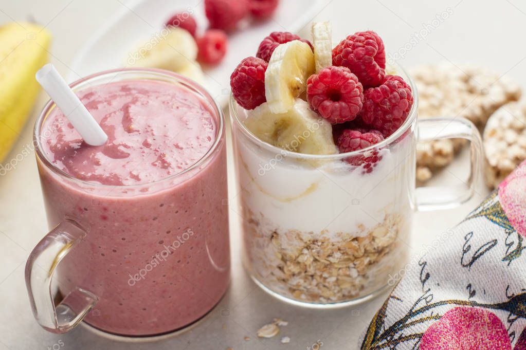 Banana, raspberry, oatmeal and yogurt smoothie and ingredients in two glass cups