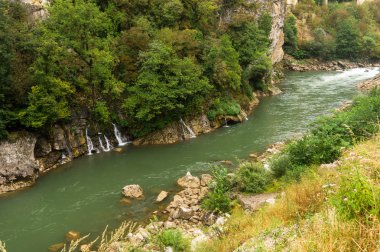 Kayalık kıyıları olan bir dağ nehrinde şelaleler