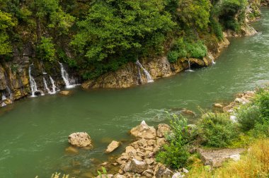 Kayalık kıyıları olan bir dağ nehrinde şelaleler