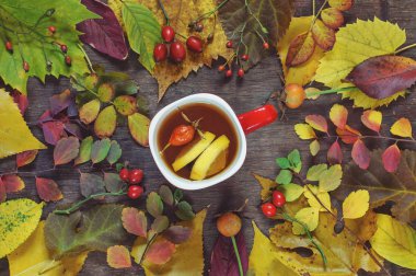 Bir ahşap üzerinde renkli sonbahar yaprakları bir arka plan üzerinde bir fincan çay