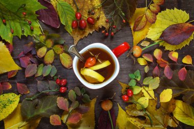 Bir ahşap üzerinde renkli sonbahar yaprakları bir arka plan üzerinde bir fincan çay