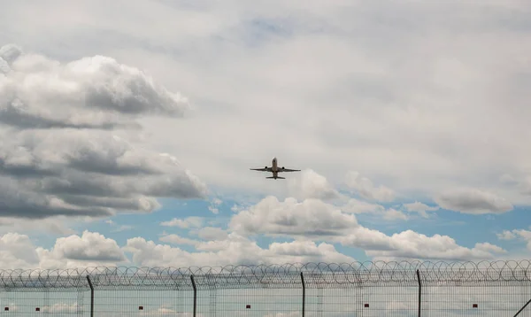 Çitin üzerindeki bulutlu gökyüzünde uçak