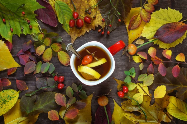 Bir ahşap üzerinde renkli sonbahar yaprakları bir arka plan üzerinde bir fincan çay