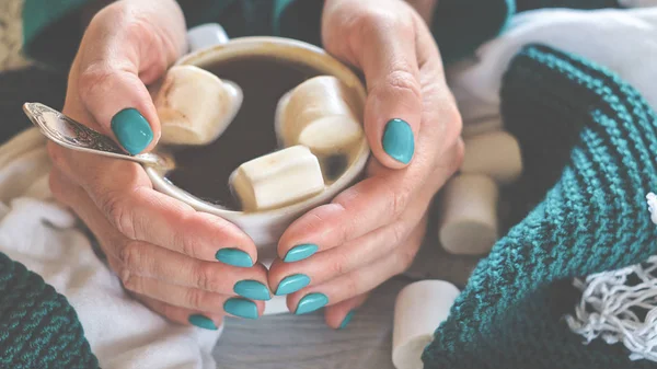 Une tasse de cacao avec guimauve dans les mains des femmes avec un ongle bleu — Photo