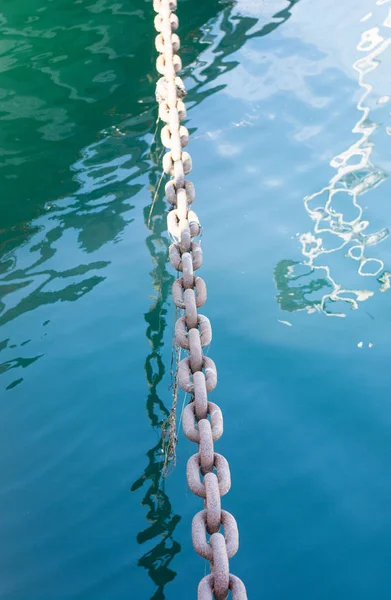 Metal thick chain reflected in blue water — Stock Photo, Image