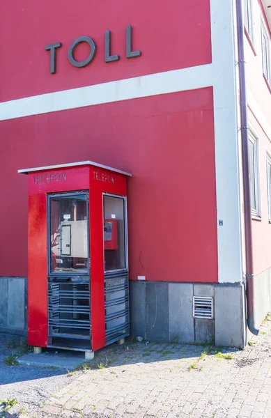 Cabina telefonica rossa vicino al muro rosso — Foto Stock