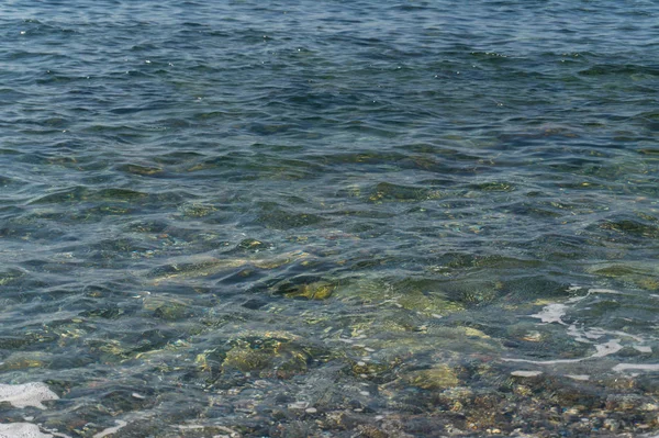 Klares Wasser und bunte Kieselsteine auf dem Meer — Stockfoto