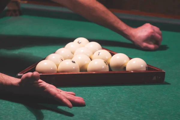 Um homem coloca as bolas em uma mesa de bilhar — Fotografia de Stock