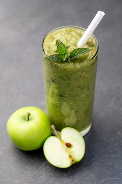 Green apple smoothie in a glass, whole and half apple