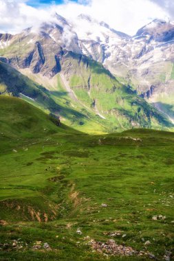 Yeşil dağ vadisi ve bulutlarda karlı dağ yamaçları, Aus