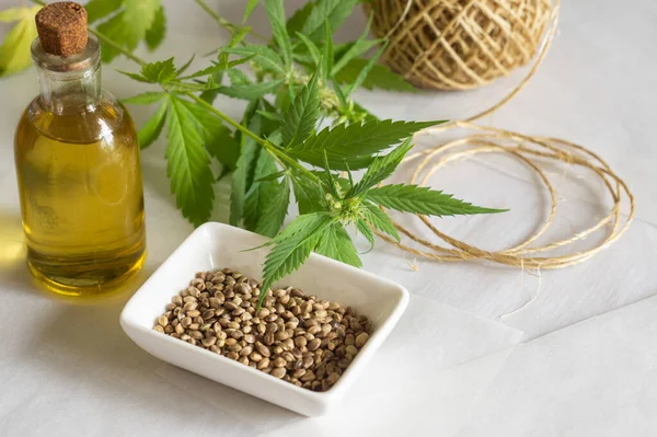 Concepto de productos de cáñamo. Botella con aceite de cannabis, madeja de hilo y planta verde — Foto de Stock