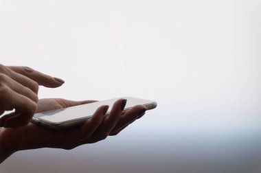 Hafif gradyan arkaplanda akıllı telefon tutan kadın eller