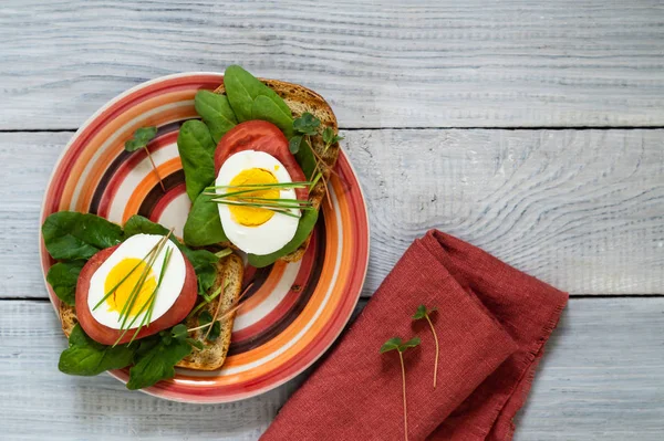Toast of unleavened bread with tomato, spinach, egg and microgreen