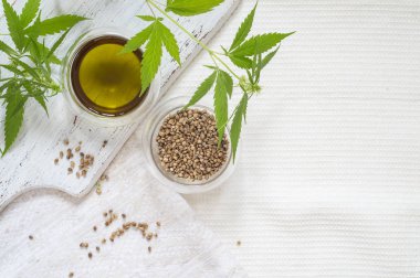 Kenevir ürünü konsepti. Tohumlar, kenevir yağı ve ev yapımı kumaş üzerine yeşil bitki