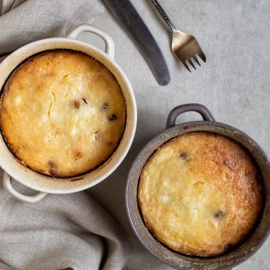 Gri masanın üzerinde süzme peynir güveci olan iki tava.