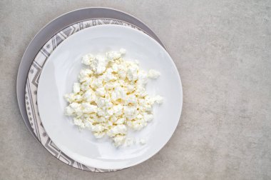 Gri arka planda beyaz tabakta süzme peynir.