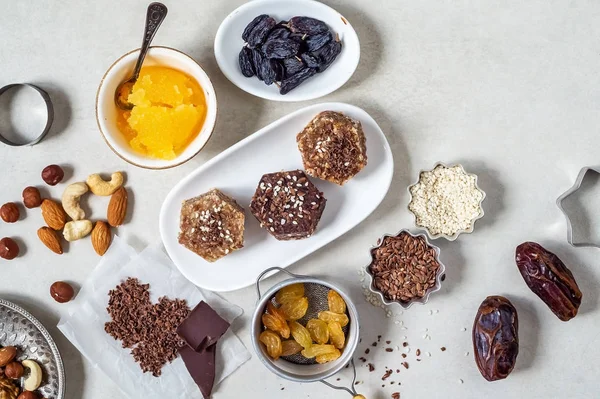 Natural useful sweets from dates, nuts, honey and raisins on a white plate. These ingredients are next on the table