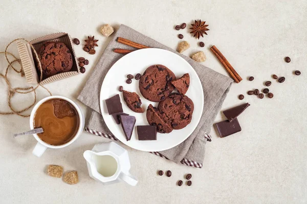 Biscuits à l'avoine avec cacao et chocolat sur une assiette blanche et dans une boîte en carton, une tasse de café et une cruche à lait — Photo
