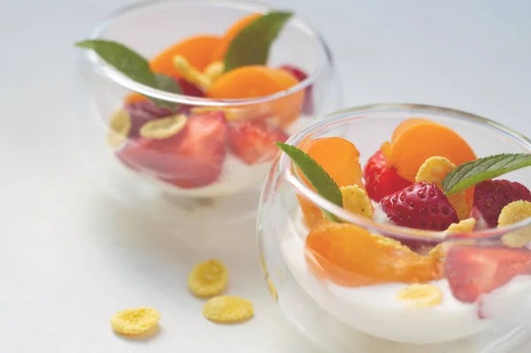 Vitamine dessert van verse aardbeien, abrikozen en cornflakes met yoghurt op een witte achtergrond — Stockfoto