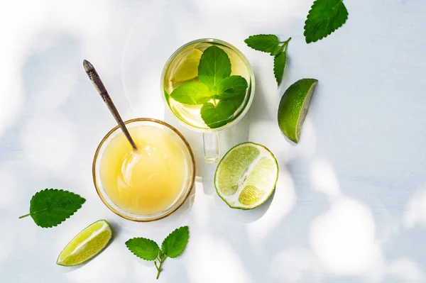 Limetten-Tee mit Minze in einer Glasschale und Honig auf weißem Hintergrund — Stockfoto