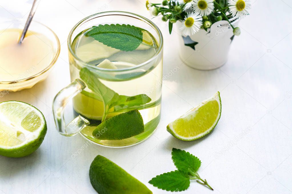 Lime tea with mint in a glass cup, honey and chamomile