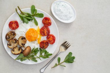 Yağda yumurta, domates, mantar, purslane ve sos beyaz tabakta.