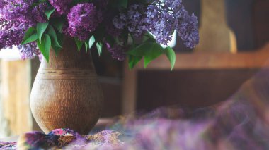 Sürahide bir demet leylak ve siyah ahşap bir masada ipek bir eşarp. Retro biçimi