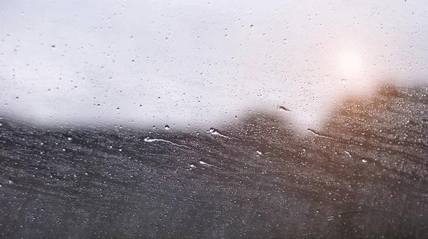 Drops and horizontal drips of rain on a car window