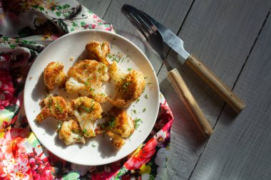 Ekmek kırıntılarında kızartılmış karnabahar ve beyaz bir tabakta dereotu.