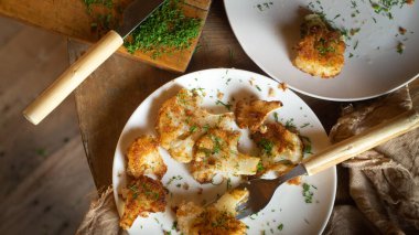 Ekmek kırıntılarında kızartılmış karnabahar ve beyaz bir tabakta dereotu.