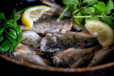 Çiğ nehir balığı soğanlı, limonlu, otlu, biberli ve tuzlu, kızartılmaya hazır.