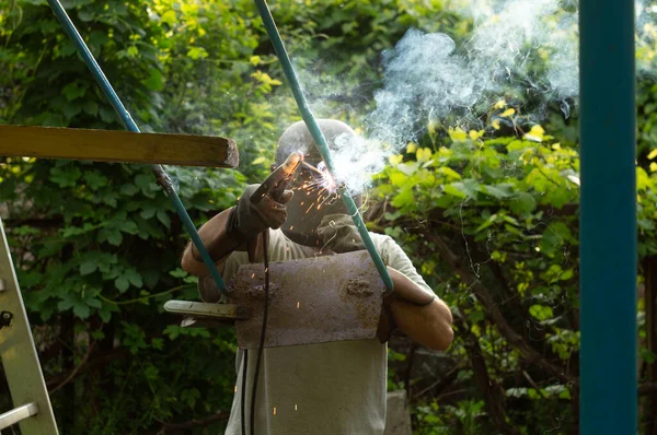 Electric Welding Man Repairs Children Swing — Stock Photo, Image