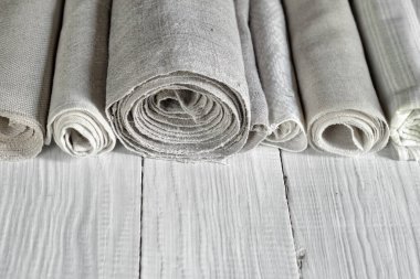 Eski ev yapımı ve modern fabrika keten kumaşlar beyaz ahşap bir masa üzerinde rulo kumaşlar