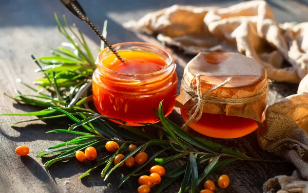 Cam kavanozlarda deniz dikenli diken reçeli, dal ve taze meyveler