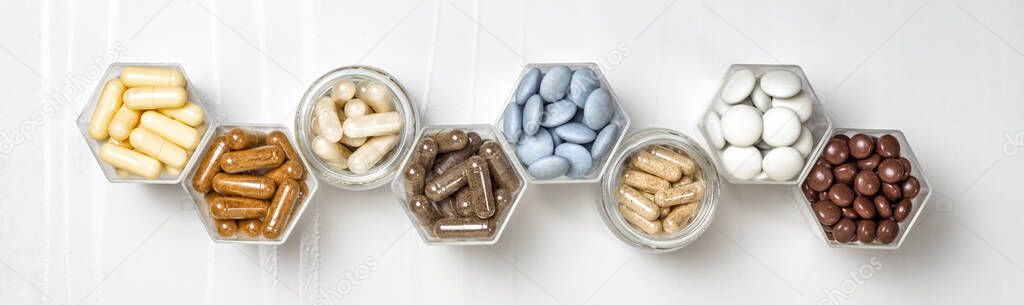 Various capsules and pills with dietary supplements or medicines in hexagonal jars are in the form of a honeycomb