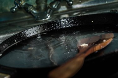 Bulaşıkları yıkıyor. Lavaboda pan.