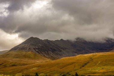 Alçak bulut ve sis, Skye Adası Glen Brittle 'daki siyah Cuillin dağ sırasının üzerinde yuvarlanıyor.