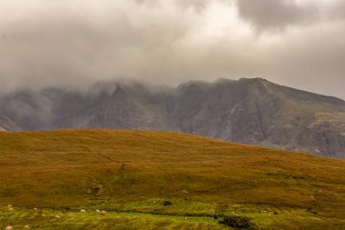Alçak bulut ve sis, Skye Adası Glen Brittle 'daki siyah Cuillin dağ sırasının üzerinde yuvarlanıyor.