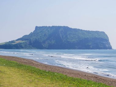 Arka planda Seongsan Ilchulbong volkanı olan Gwangchigi Sahili manzarası. Jeju Adası, Güney Kore 'de.