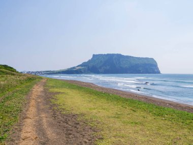 Arka planda Seongsan Ilchulbong volkanı olan Gwangchigi Sahili manzarası. Jeju Adası, Güney Kore 'de.