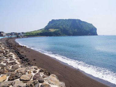Arka planda Seongsan Ilchulbong volkanı olan Gwangchigi Sahili manzarası. Jeju Adası, Güney Kore 'de.