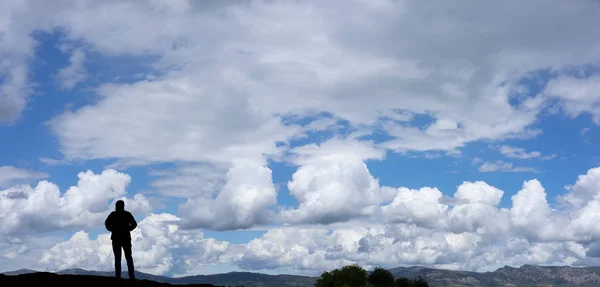 Man who has reached the top of the mountain and the sky with clouds in the background.