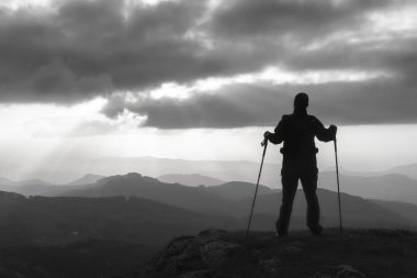 Güneş bakan bir dağ tepesinde uzun yürüyüşe çıkan kimse.