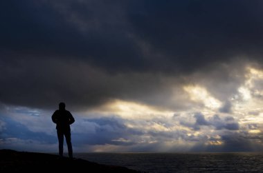 Adam arka plan ve bulutlu hava deniz ile dağ üstüne bir ceket ile