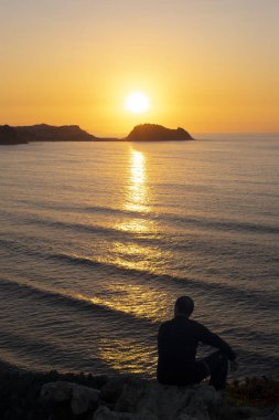 Günbatımı'nın kıyısında oturan hayran adam