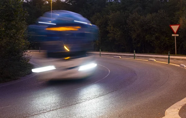Headlights of the approaching bus on the road at night.