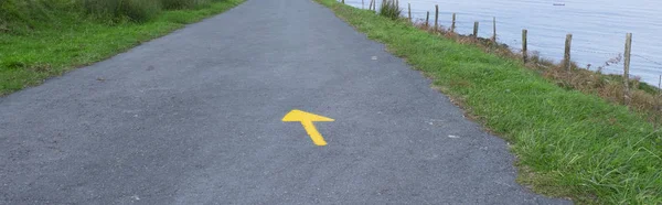 Yellow arrow on the road, mark of the road to Santiago