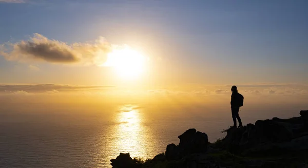 Man on top of the mountain watching the sunset over the sea, Basque Country, Spain