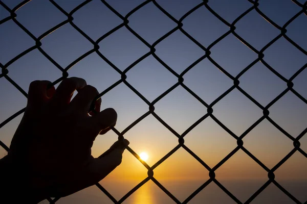 Özgürlük Için Zincir Bağlantı Çit Üzerinde Tutarak Arka Planda Güneş — Stok fotoğraf